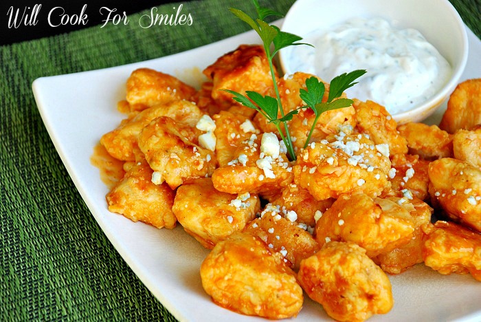 buffalo boneless wings on a white plate with a small sauce and ranch on upper right corner of plate all on a green placemat