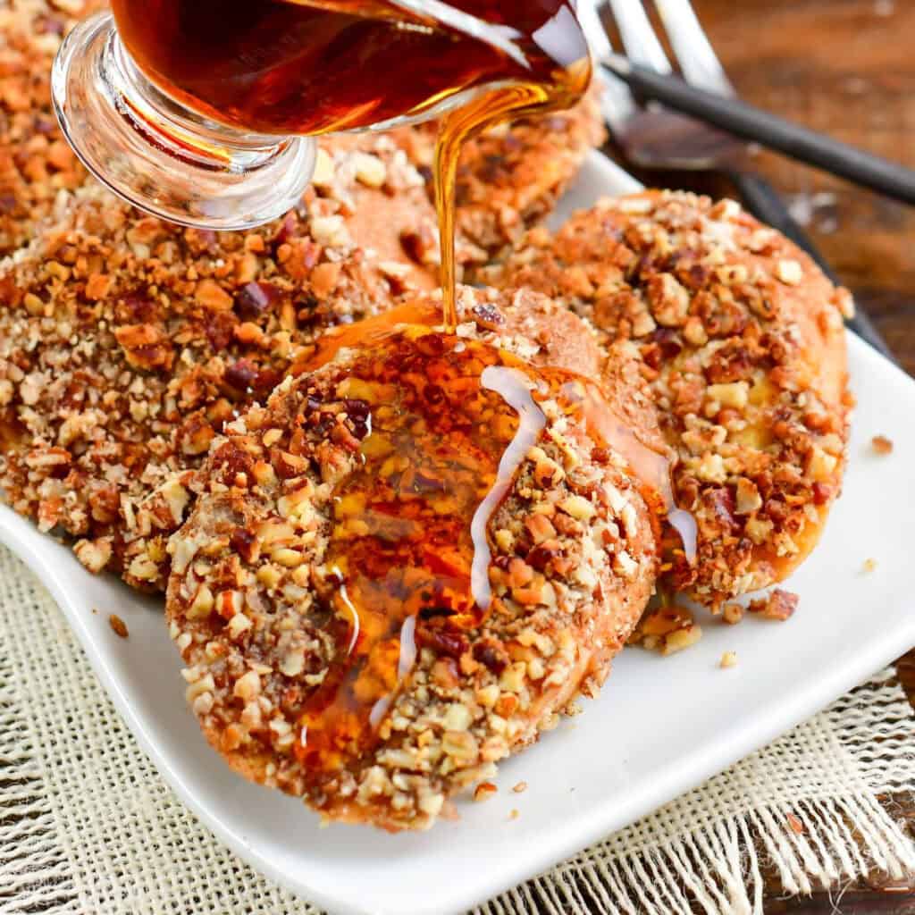 pouring maple syrup over a slice of pecan French toast.