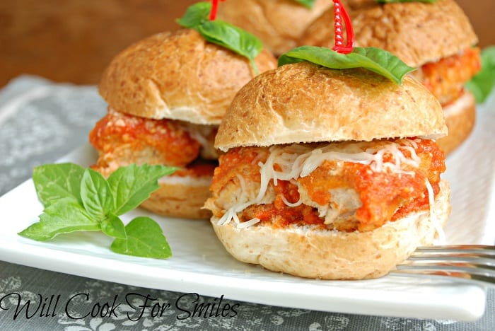 4 chicken parmesan sliders on a white rectangular plate on a white and grey cloth on woodem table