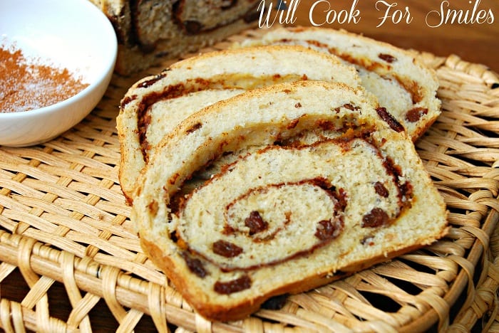 2 slices of pumpkin spice swirl bread on a wicker tray with a small white bowl of cinnamon to the left