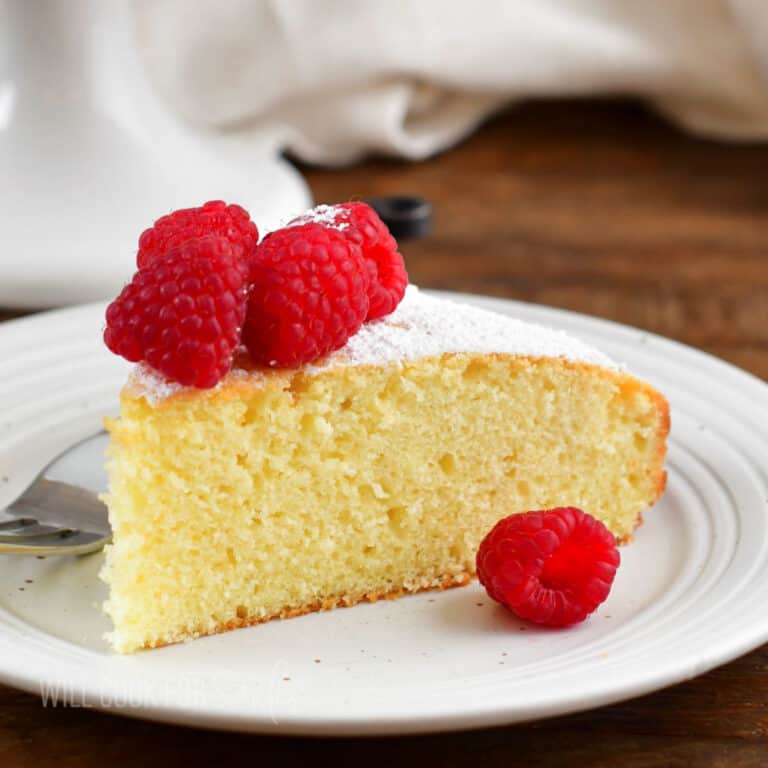 closeup of Irish tea cake on a white plate with raspberries.