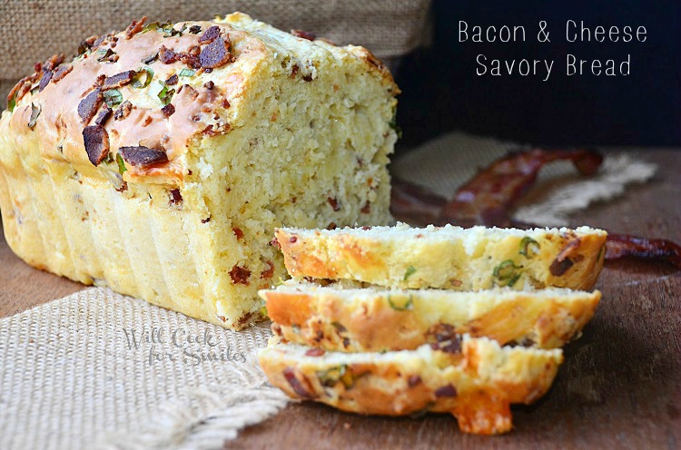 sliced bacon cheese savory bread on a wood cutting board with 2 slices of bacon to the right in background