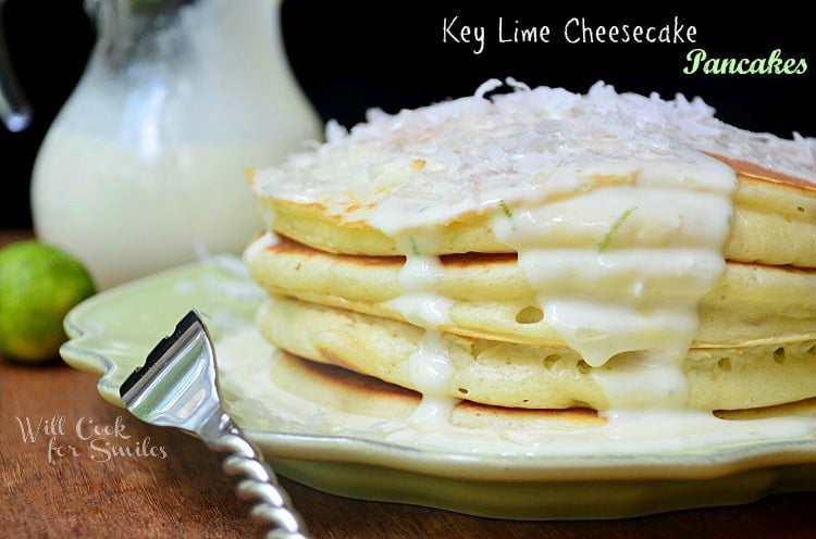 key lime cheesecake pancakes stacked on decorative lime green plate and fork with bottle of syrup in background to the left shot from front