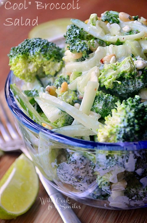 Cool-Broccoli-Cucumber-Salad is served in a glass bowl. A fork is to the left of the bowl, as well as a lime wedge.