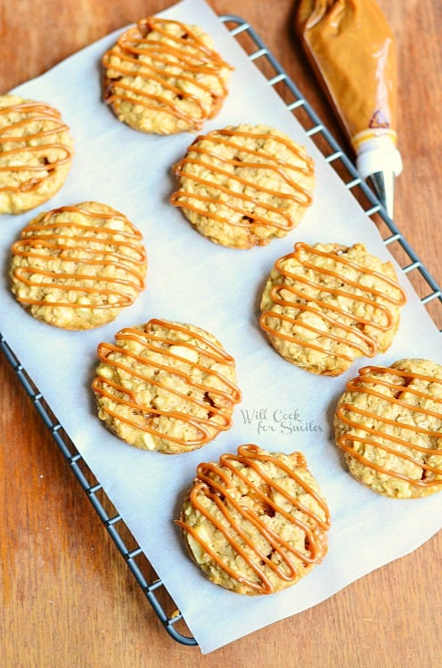 several dulce de leche apple caramel oatmeal cookies on cooling rack with wax paper on wood table