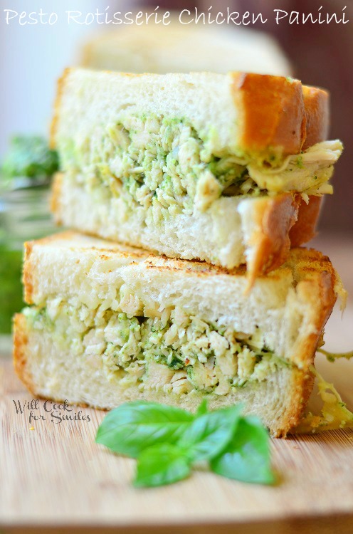 half of sandwich on top of the ther half dilled with pesto chicken salad and leaves of basil next to it