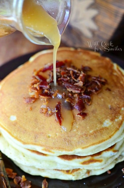 Maple Bacon Pancakes staked on a plate and pouring syrup over it 