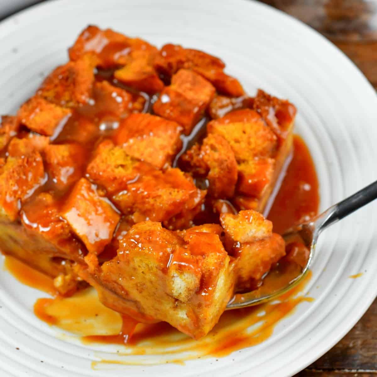 cutting through a piece of pumpkin bread pudding with a fork.