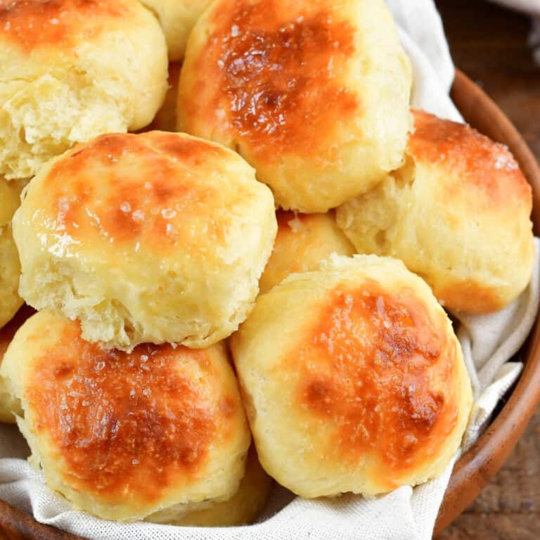 closeup squared view of several potato rolls in a bowl.