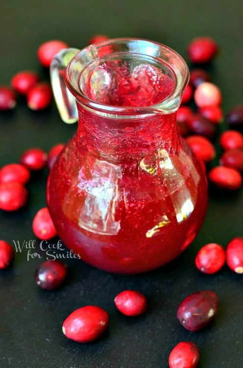 Cranberry Syrup in a glass with a spot with cranberries on a plate 