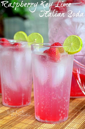 raspberry key lime Italian soda on a wood mate with raspberries and lime for garnish 