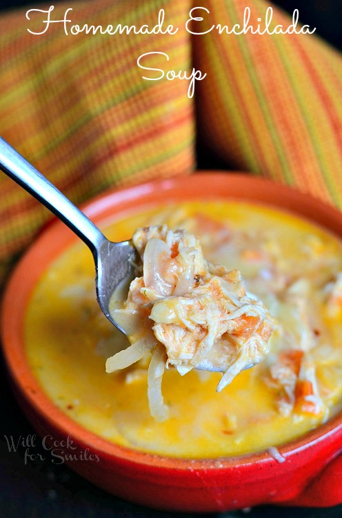 Superficie cremosa di pollo enchilada con una cucchiaiata di panna acida sopra in una ciotola rossa con un cucchiaio che ne estrae un po fuori 