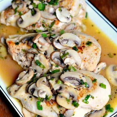 black and white decorative rectangular plate on a wood table with stuffed chicken marsala and a white napkin in the background