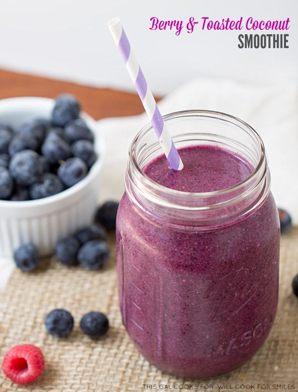 berry smoothy in a mason jar and a bowl of blueberries to the left 