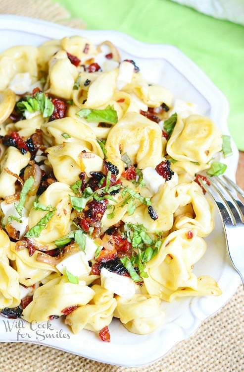 Caprese Tortellini Bowl in a white serving bowl with a fork to the right of the bowl 