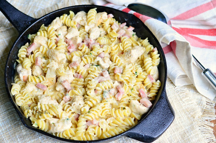 Chicken Cordon Bleu Pasta in a cast iron pan with a red and tan dish towel 