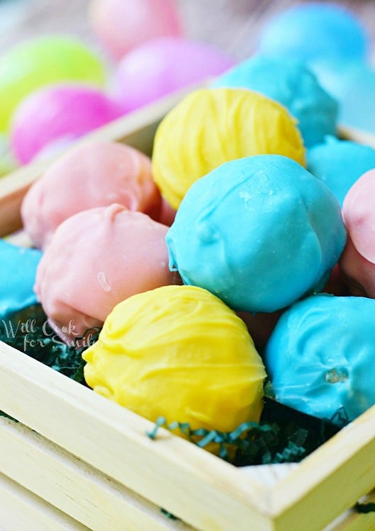 multi colored golden easter truffles in a wooden basket with shredded paper as grass