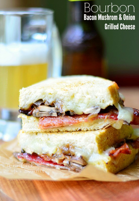 Bourbon Bacon Mushrooms & Onion Grilled Cheese cut in half on a piece of wax paper on a wood cutting board 