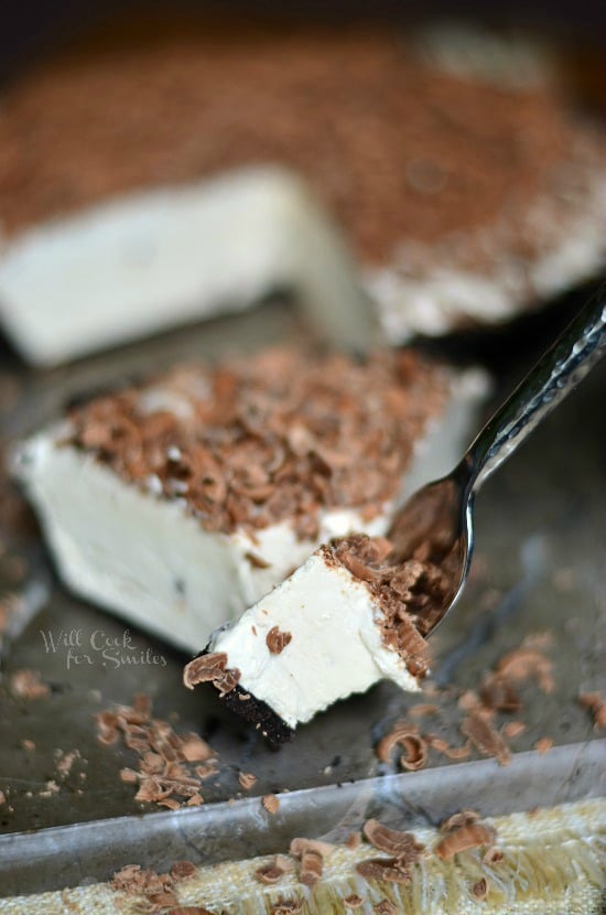 1 slice of Mocha Ice Cream pie on a marble slab cutting board in front of rest of pie with a fork pulling out a portion of pie from slice