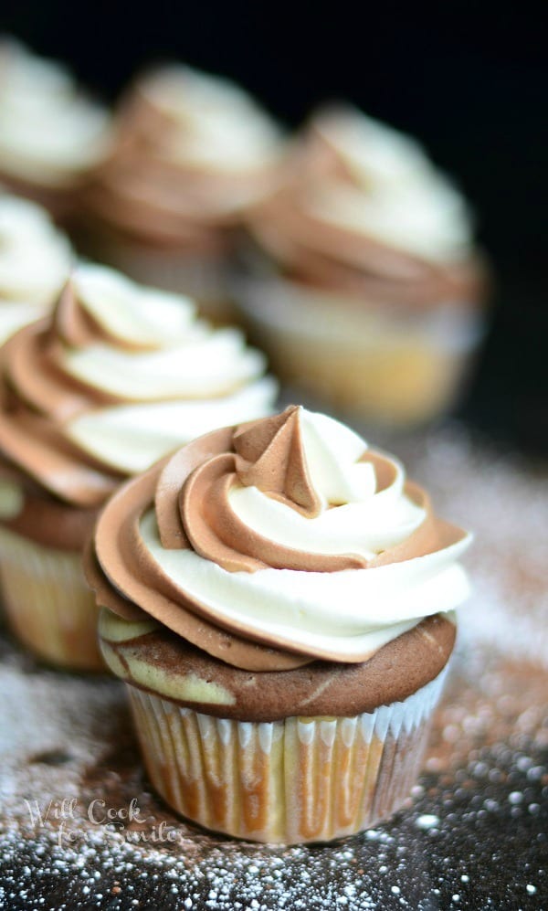 Marble Cupcakes close up on a black counter top with powdered sugar sprinkled on the counter 