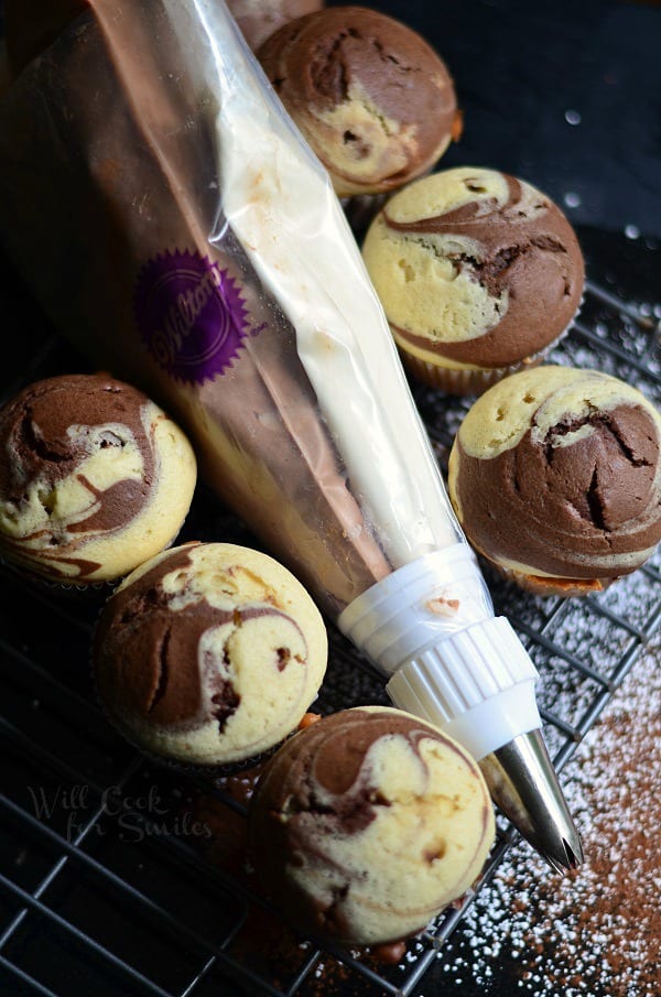 Marble Cupcakes on a cooling rack with chocolate and vanilla frosting in a pipping bag