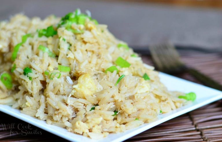 close up view of white rectangle plate with crab fried rice all on a bamboo placemat