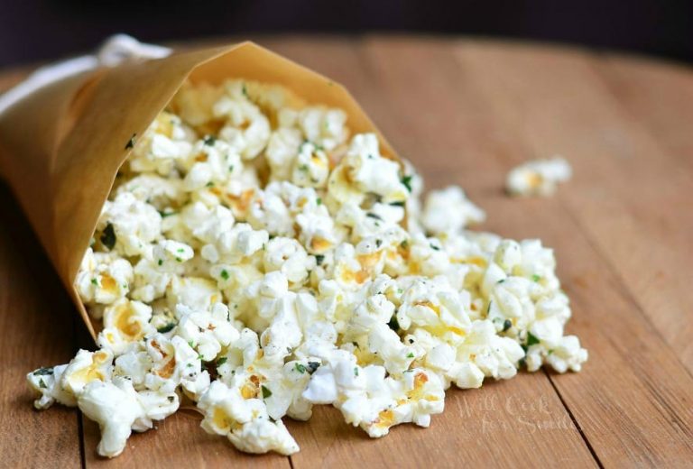 close up view of wax paper rolled into cup holding a heaping portion of Italian Truffle oil popcorn on a wood table