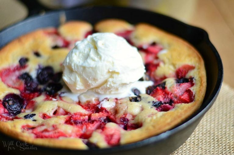 clsoe up of trile berry skillet tea cobbler topped with ice cream on a brown placemat on a wood table