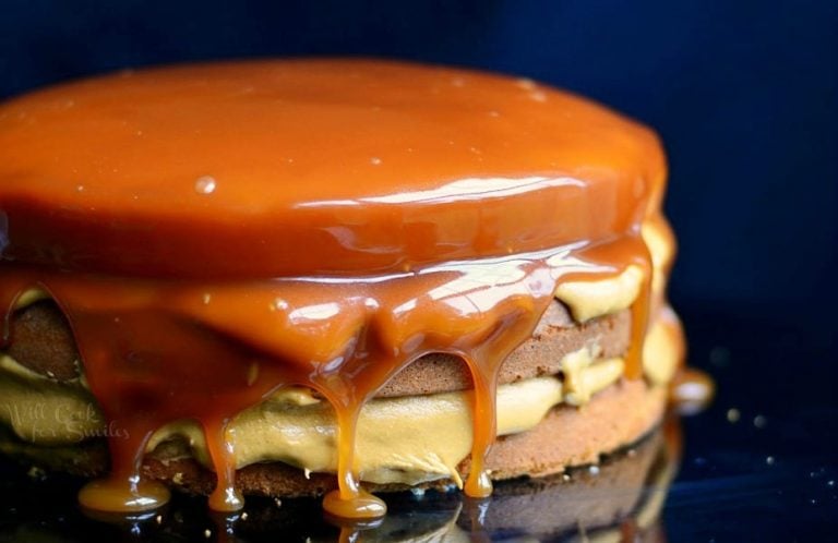 Close up view of Whole caramel cake on a black cake presenter with a black background