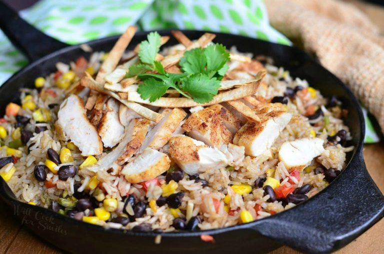 view from above of black skillet with chicken tortilla rice dish on a wood table with green and white cloth in the background