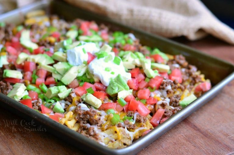 small baking tray with Taco Waffle nachos on a wood table with a brown cloth in the background