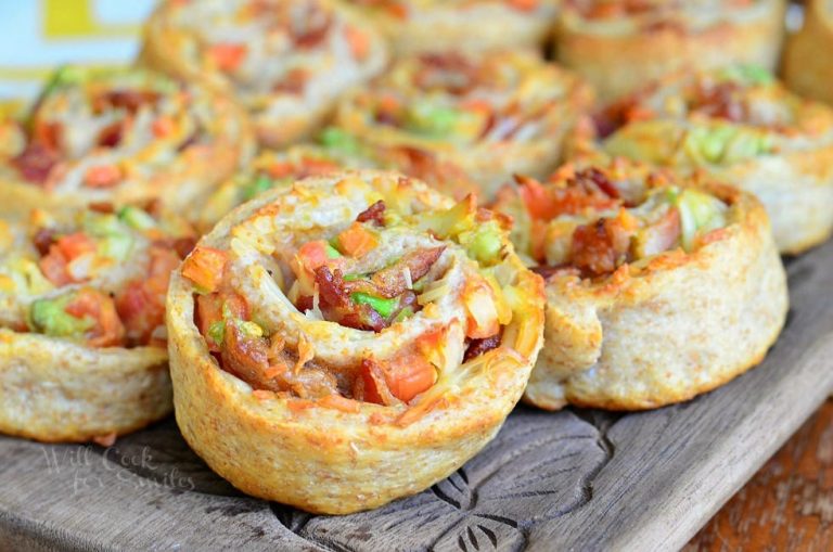 clsoe up view of 10 bacon gruyere pizza pinwheels sitting on a wood tray