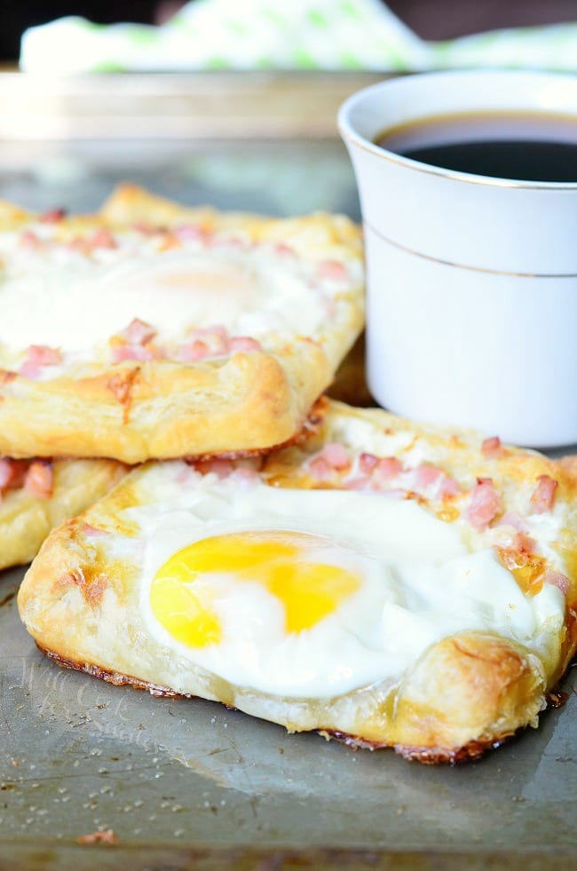 shignled pile of Ham egg cheese breakfast pastry and a cup of coffee on a sheet try and table