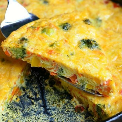 Fork lifting up one portion of vegetable and cheese overload breakfast bake over rest of dish