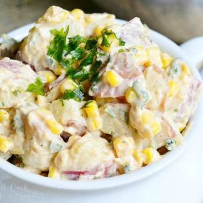 view from above of chipotle ranch potato salad in a white crock on a wooden table