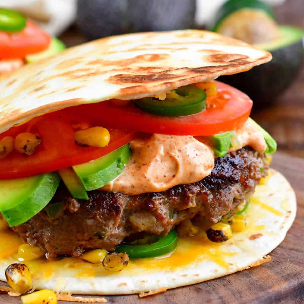 Cheeseburger on a tortilla with tomatoes, avocado, jalapenos, and chipotle mayo.