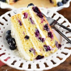 A slice of blueberry cake on a plate with a fork to the right.