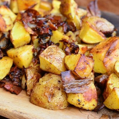 close up view of cutting boared covered with brown roasted potatoes