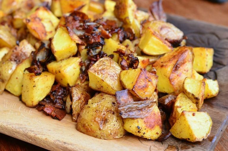 close up view of cutting boared covered with brown roasted potatoes