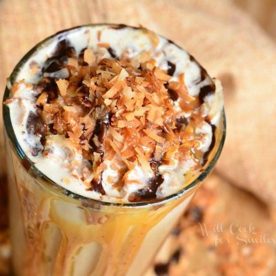 view from above of pint glass filled with samoas frozen coffee on a wooden table with coconut shaving scattered around the bottom of the glass