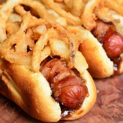 close up view of bbq bacon crsipy onion hot dogs on a wooden table viewed close up