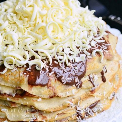 Crepe Cake on a white plate covered with chocolate and white chocolate shavings