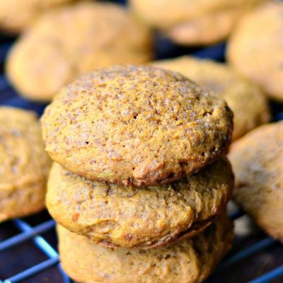 3 pumpkin pudding cookies stacked on a wire cooling rack with more cookies in the background