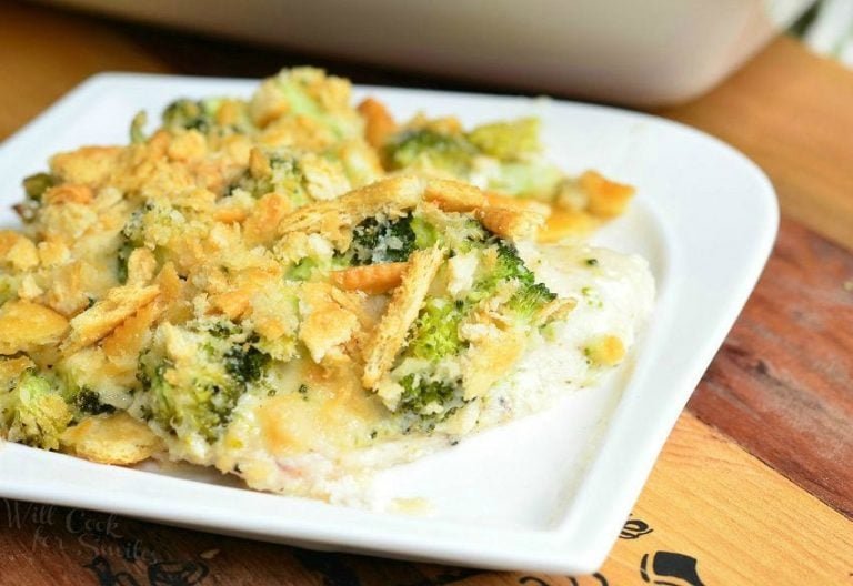 white decorative square plate with 1 portion of broccoi cheese chicken and a white baking dish filled with the rest of the entree in the background as viewed close up