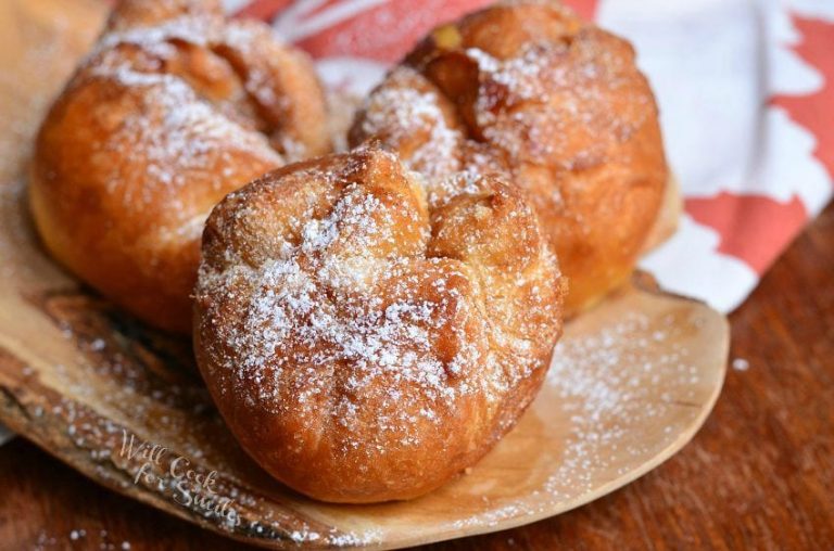 3 easy apple pie doughnuts on a decorative wooden plate with a white and red fall festive cloth in the background