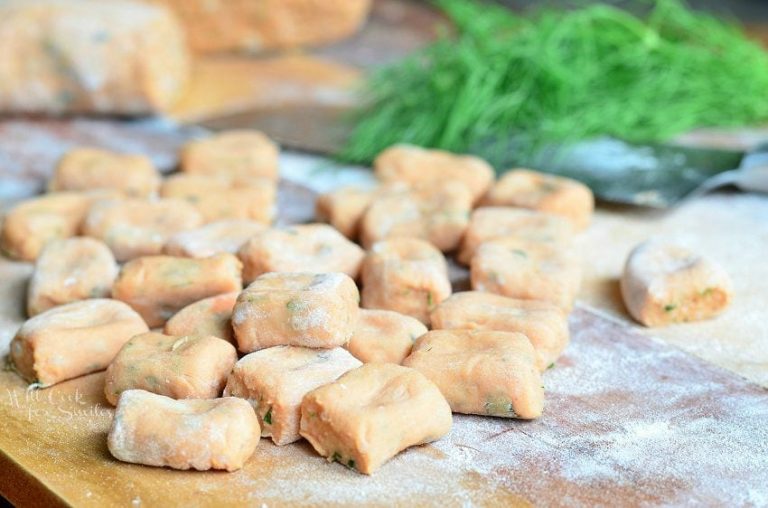 picture of uncooked homemade tomato herb gnocchi on a rolling mat covered lightly in flour