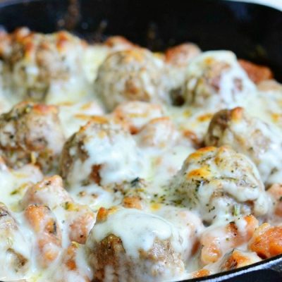 black skillet with meatball and gnocchi bake with a white and red cloth in the background