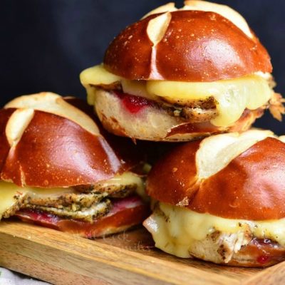 4 cranberry asiago turkey sliders stacked on a wooden cutting board viewed close up