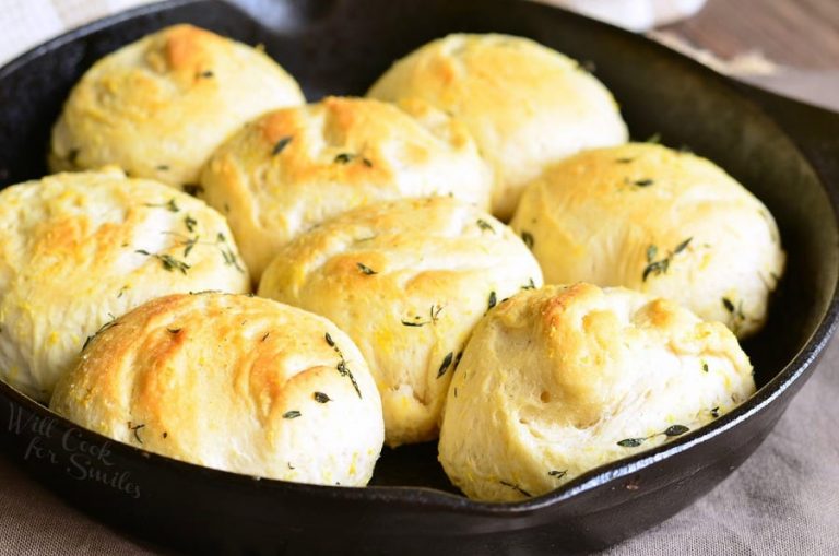 black skillet holding lemon thyme biscuits on a wooden table with a white and tan cloth in the background viewed close up