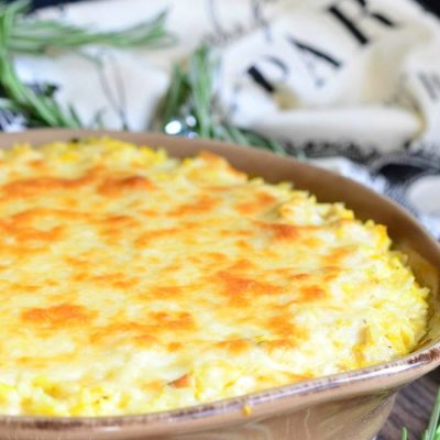 Large round baking dish filled with turkey butternut squash and mascarpone rice casserole on a wood table with a white towel in the background